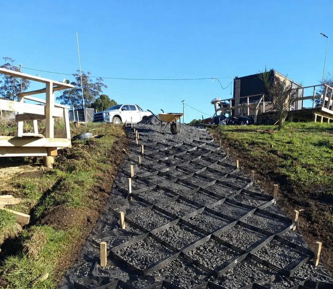 Geocelda HDPE instalada en un acceso en pendiente, rellena con grava — MF Design